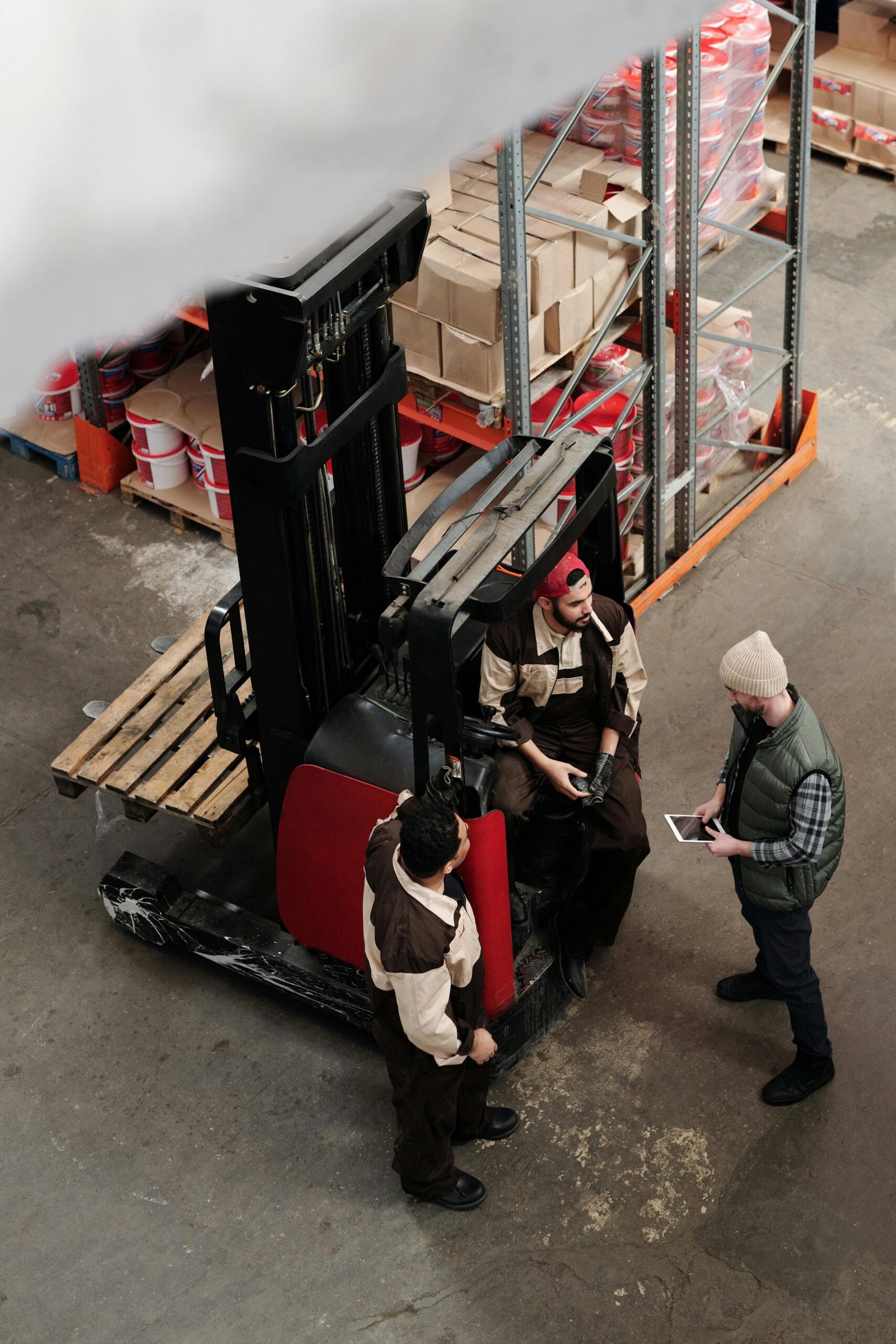 Home Overhead view of warehouse workers having a meeting with forklift equipment. Collaborative workplace scenario.