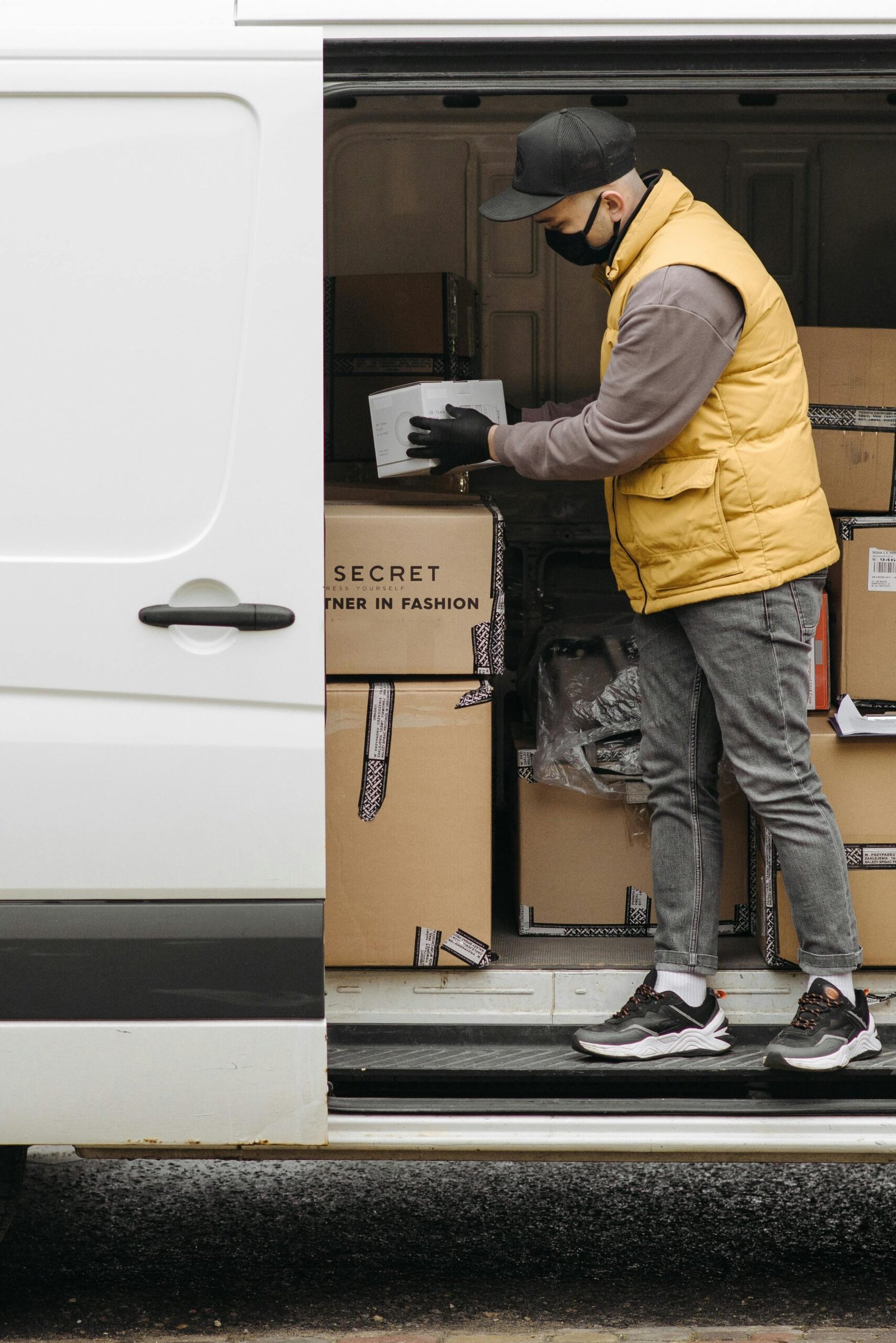 Home Deliveryman arranging packages in white van for efficient distribution.